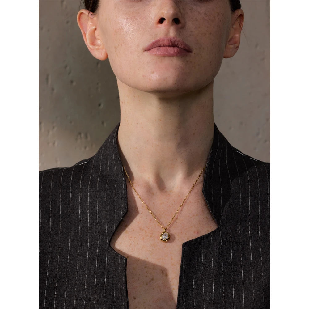 Mulher usando colar de ouro com pingente de pedra em blazer risca de giz preto