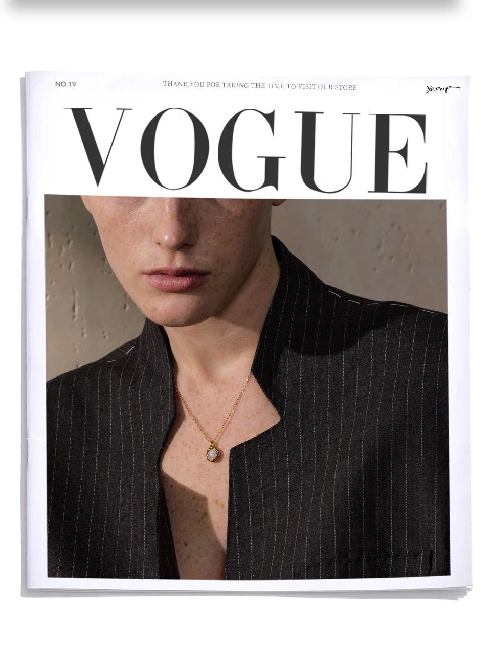 Mulher usando colar dourado e blazer risca de giz na capa da revista Vogue.